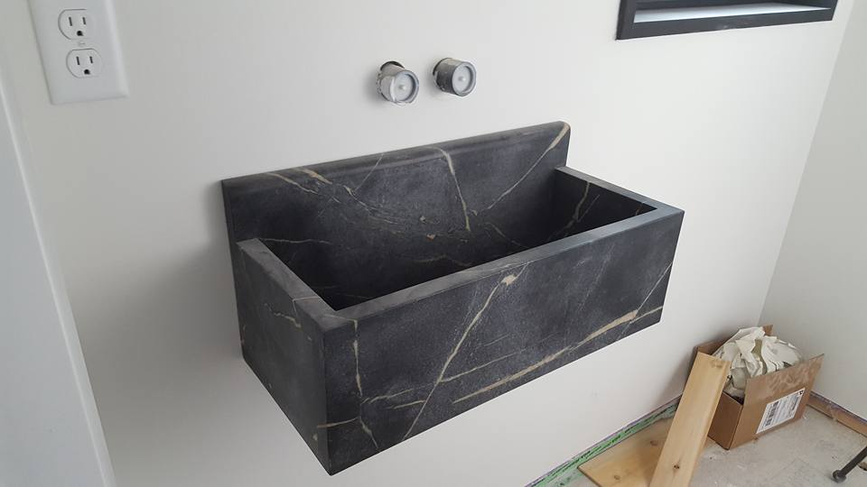 Custom dark stone wall-mounted sink made by Stone Surface